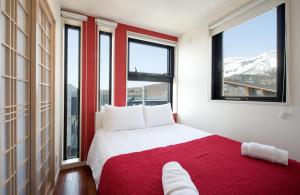 二世古Udelka A的卧室设有红色和白色的床和窗户。