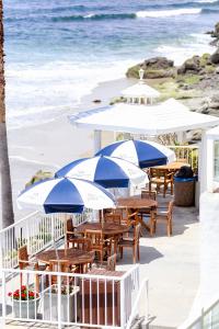 拉古纳海滩卡普里拉古娜海滩精品酒店的海滩上带桌子和遮阳伞的庭院