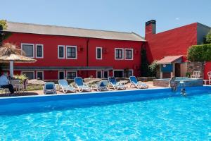 坦迪尔卡萨格兰德旅馆的一个带椅子的游泳池以及一座红色的建筑