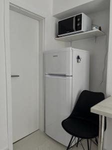 斯塔里格勒Secret Place Apartment的厨房配有白色冰箱和黑椅