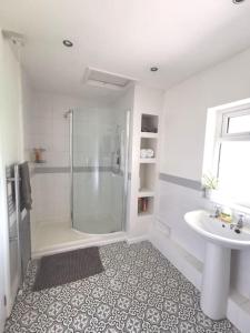 巴顿尼德伍的Canalside Cottage的带淋浴和盥洗盆的白色浴室