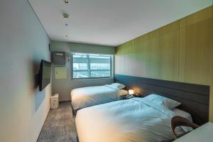 仁川市仁川机场1号航站楼过境酒店的一间卧室设有两张床和窗户。