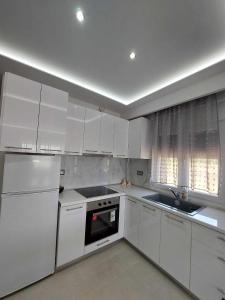 尼亚·蒙达尼亚Marane luxury suites的白色的厨房配有白色橱柜和水槽