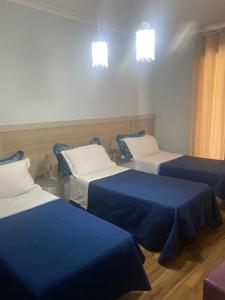 卡塔尼亚B&B Elios Rooms的一间设有三张床的客房,配有蓝色和白色的床单