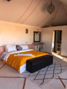 姆哈米德Desert Luxury Camp的一间卧室配有一张带橙色毯子的大床