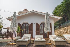 埃斯托利尔Villa Pietra Estoril Eco Guesthouse的房屋前面有椅子和遮阳伞