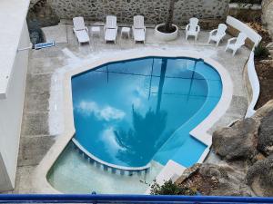 阿卡普尔科Secretos del Sol Acapulco villas a 5 minutosdel mar的享有带椅子和棕榈树的游泳池的顶部景致
