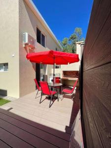贝拉维斯塔Casa para 4 personas en vista24uy, Bella Vista, Maldonado的庭院配有红色的椅子和桌子以及遮阳伞。