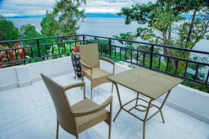 吉塞尼KIGUFI HILL, Agape Resort & Kivu Edge的阳台配有三把椅子和一张桌子,享有水景。