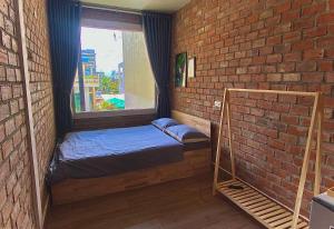 岘港IKIGAI Dorm Hostel - Danang Beach的小房间,设有床和砖墙