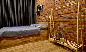 岘港IKIGAI Dorm Hostel - Danang Beach的一间卧室设有一张床和砖墙