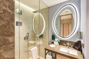 撒马尔罕Hilton Garden Inn Samarkand Afrosiyob的浴室配有盥洗盆和带镜子的淋浴