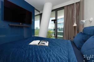 米兹多洛杰Wave Międzyzdroje - Luxury 2 Bedroom Suite with Salon and Kitchen的一间卧室配有一张蓝色的床、电视和两本书