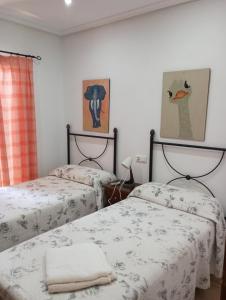 维拉Casa Brisa Marina Vera的一间卧室配有两张床,墙上有两幅画作