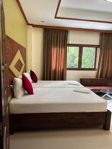 通奈潘海滩布达拉克撒旅馆的一间卧室配有一张带红色枕头的大床