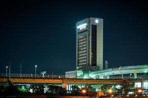 泉大津市Kanku Izumiotsu Washington Hotel的一座高大的建筑,上面有灯,晚上