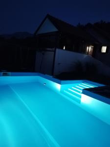 特雷比涅Trebinje - Lastva - Vikendica Vukovic-的游泳池在晚上点亮,灯光蓝色