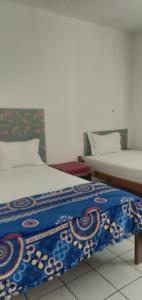 克里穆图Hidayah homestay的一间卧室配有两张带蓝白色毯子的床
