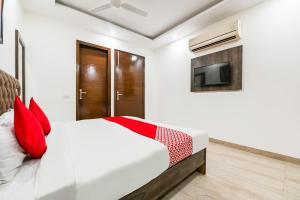 新德里OYO 72284 Premium Rooms Chhatarpur的一间卧室配有一张带红色枕头的床和一台电视。