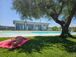佩斯卡拉Luxury Pool Suites - Città Bianca的游泳池旁的毛巾上躺着的人