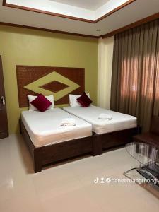 通奈潘海滩布达拉克撒旅馆的一间卧室配有两张带红色枕头的床