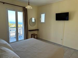 拉瑟解放村公寓式酒店的一间卧室配有一张床、一台电视和一个阳台
