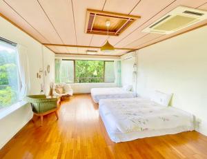 石垣岛イリワ -stay&coffee iriwa-的一间卧室设有两张床、一张桌子和一个窗口。