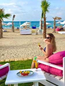 亚历山大天堂海滩度假酒店的坐在海滩长凳上吃食物的女人