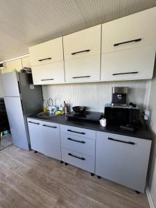 Sanctum Glamping的厨房配有白色橱柜、水槽和冰箱。