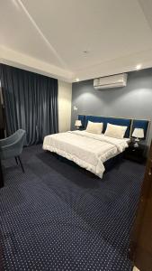 哈伊勒منازل الشمال للشقق المخدومة Manazel Al Shamal Serviced Apartments的一间卧室配有一张大床和一把椅子