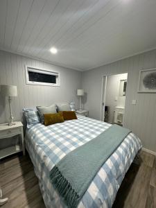 惠灵顿BENROSE FARM COTTAGES的一间卧室配有一张大床,配有蓝白色的格子布毯
