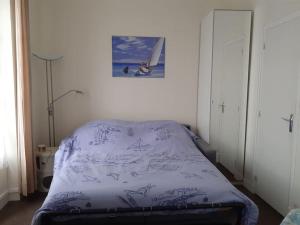 卡布尔Cabourg Charmant studio centre ville RUE DE LA MER的一间卧室配有一张带紫色毯子的床