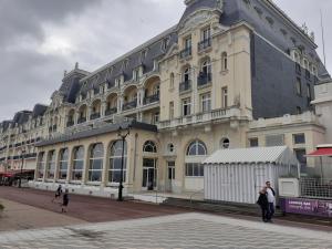 卡布尔Cabourg Charmant studio centre ville RUE DE LA MER的一座大型建筑,前面有人