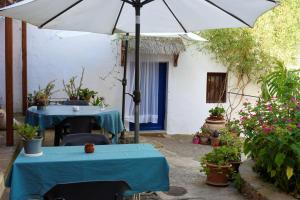 AlbuñolLa Casita Azul - Casa típica andaluza的庭院设有两张桌子和一把伞