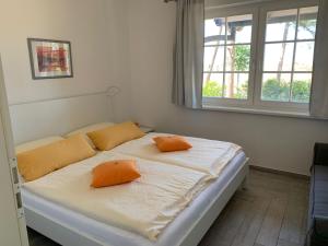 阿伦斯霍普简和贾纳度假公寓的一间卧室配有一张带两个橙色枕头的床