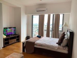马尼拉Century Properties/ Aqua Iguazo Condo Unit的一间卧室设有一张床、一台电视和一个窗口。