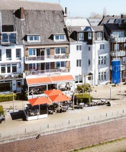 埃默里希Hotel Rheinpromenade8的一座带橙色伞和桌子的建筑