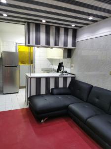 迪拜Cloud9 Premium Hostel的一间带黑色沙发的客厅和一间厨房