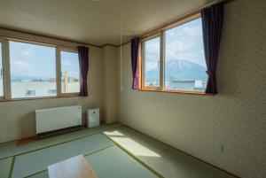 俱知安町Ezo Fujiya Niseko House - Vacation STAY 14767的客房设有电视和2扇享有山景的窗户。