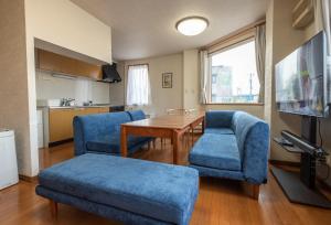俱知安町Ezo Fujiya Niseko House - Vacation STAY 14767的一间带蓝色椅子和一张桌子的客厅以及一间厨房
