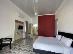 MuntokPondok Sahang Cottages的卧室配有白色的床和红色的墙壁