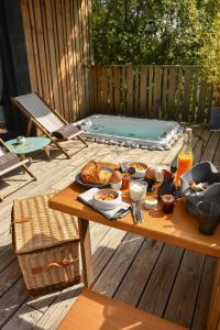 尼姆Bien Loin d'Ici Spa B&B的一个带热水浴缸的甲板上的野餐桌和食物