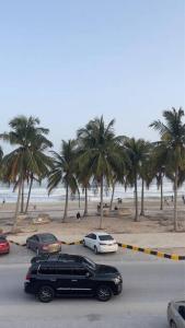 塞拉莱Fully Furnished 2bedroom apartment, Salalah, Oman的停车场有汽车,海滩上种有棕榈树