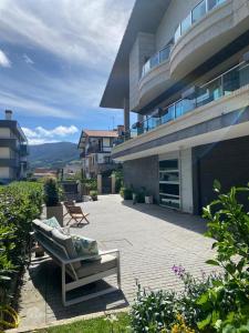 巴基奥Bakio Beach House的一座大建筑,设有一座配有沙发的庭院