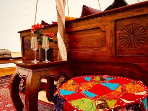 玛丽费莱德tent delhi a b&b in a luxury glamping style的一张木床,桌子旁边放着一张桌子,配有酒杯