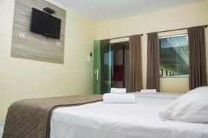 巴纳伊巴Pousada Aeroporto的一间卧室设有两张床,墙上配有电视。