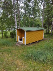 HoutskariMysig Stuga På Houtskär的田间中的一个黄色小房子
