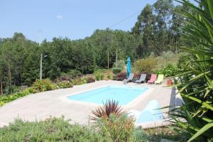 EspinhoCasa Quelha da Presa的花园内的游泳池,配有两把椅子和一把遮阳伞