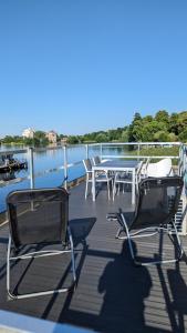 菲尔斯滕贝格Waterview - Schwimmendes Ferienhaus auf dem Wasser mit Blick zur Havel, inkl Motorboot zur Nutzung的甲板上配有两把椅子和一张桌子,