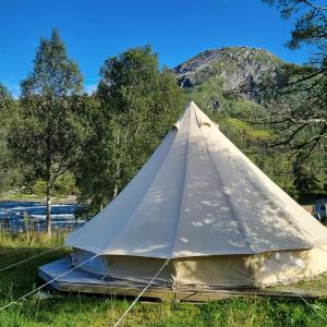 ViksdalenFlatheim Glamping的河边草上的白色帐篷